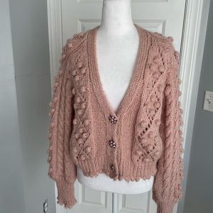 Pink V neck sweater with jeweled buttons.